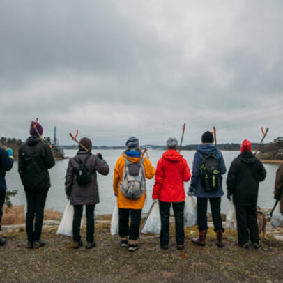 People standing in a row by the sea in Helsinki.