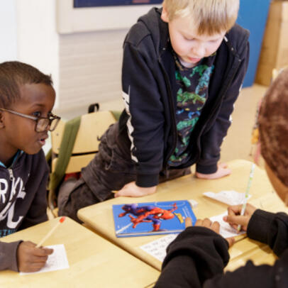 Children are doing schoolwork together in a classroom.