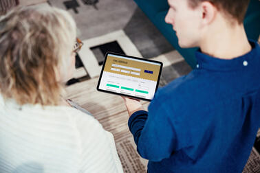 Kaksi henkilöä katsoo tablettitietokoneelta Päätökset-palvelun etusivua.