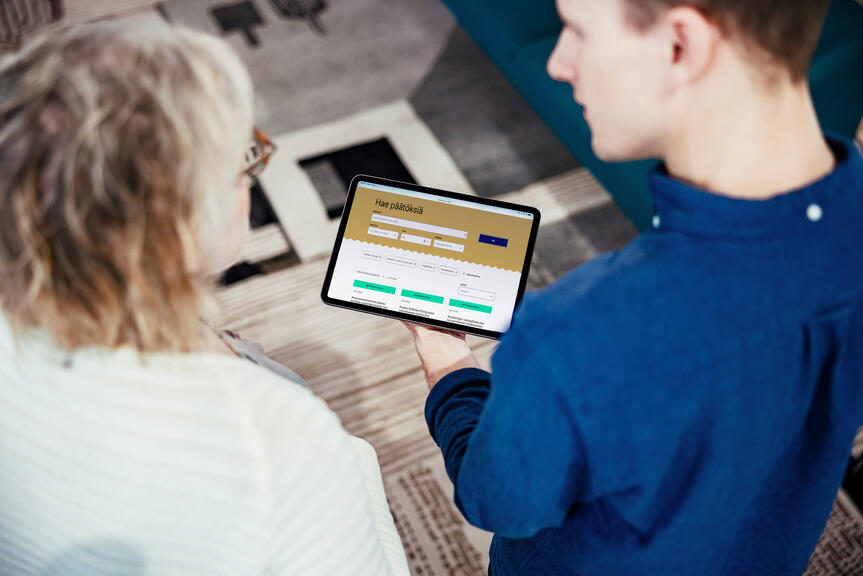 Kaksi henkilöä katsoo tablettitietokoneelta Päätökset-palvelun etusivua.