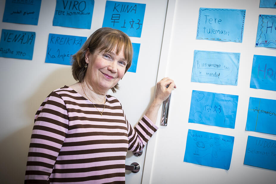 Tiina Kähärä näyttää erikielisiä tekstejä seinällä